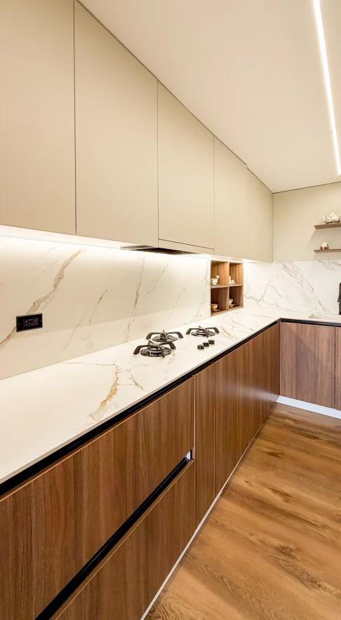 Cocina remodelada con muebles de madera, gabinetes claros y mesón de acabado marmoleado.
